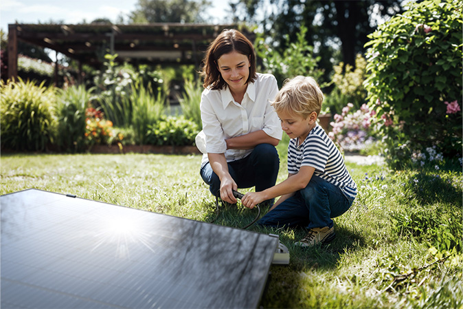 Mutter und Kind schließen ein Solarpaneel im Garten an – ideal für die Anwendung mit EcoFlow STREAM Pro