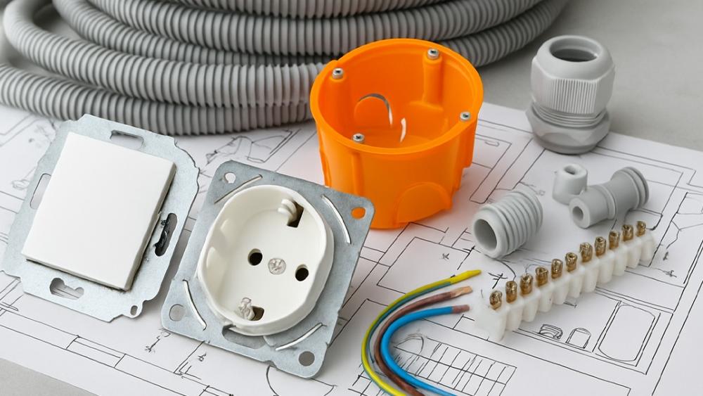 Elektroinstallationsmaterial auf einem Bauplan mit Hohlwanddose, Leerrohr, Klemme und Drähten – Elektro Pepi