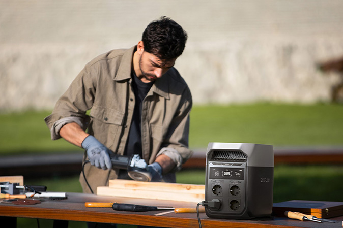 Handwerker arbeitet mit Elektrowerkzeug im Freien, betrieben über eine EcoFlow Powerstation auf dem Arbeitstisch